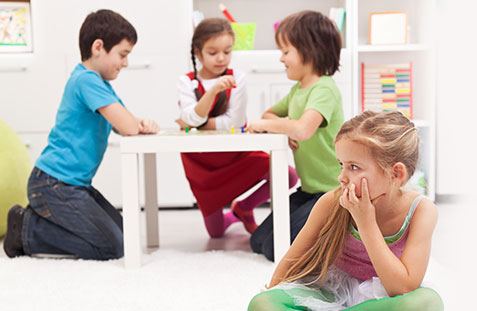 child sitting alone at school not joining in